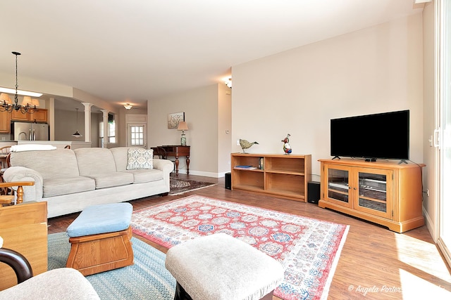 13399 Glenwood Dr, Huntley, IL 60142 - living room with decorative columns, light wood-style floors, and a chandelier