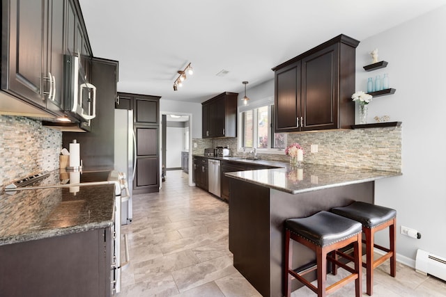 1060 Highland Ave, Lake Forest, IL 60045 - kitchen featuring baseboard heating, appliances with stainless steel finishes, a peninsula, a breakfast bar area, and decorative backsplash