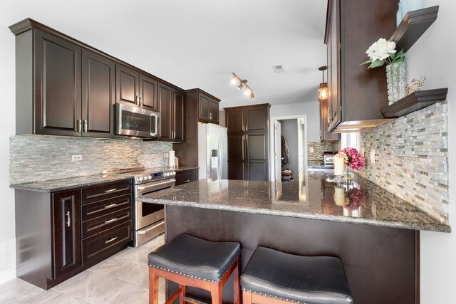 1060 Highland Ave, Lake Forest, IL 60045 - kitchen with stainless steel appliances, a peninsula, dark brown cabinets, dark stone counters, and backsplash