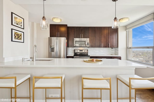 2626 N Lakeview Ave Unit 2012, Chicago, IL 60614 - kitchen with appliances with stainless steel finishes, tasteful backsplash, light countertops, dark brown cabinetry, and hanging light fixtures