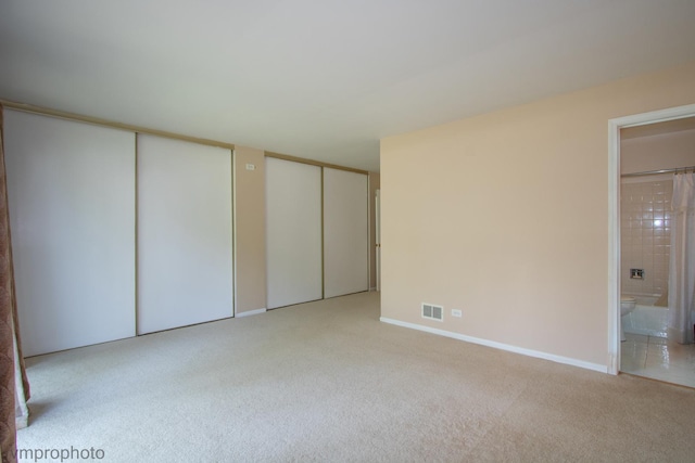 771 E Devon Ave, Roselle, IL 60172 - unfurnished bedroom featuring multiple closets, light carpet, and ensuite bath