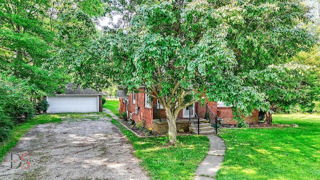305 W 3rd St, Streator, IL 61364 - view of property hidden behind natural elements featuring a front lawn, an outdoor structure, a detached garage, and brick siding