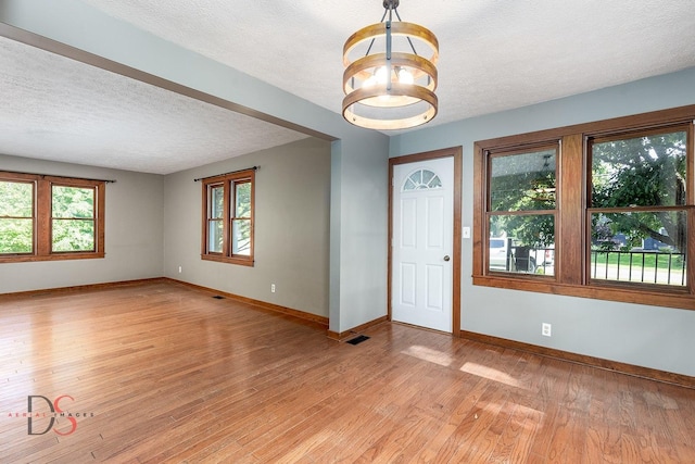 305 W 3rd St, Streator, IL 61364 - unfurnished room featuring light wood-type flooring, a chandelier, and a textured ceiling