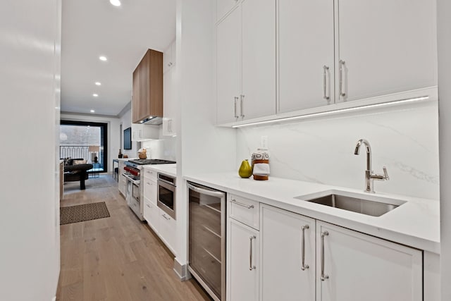 1646 N Orchard St Unit 1S, Chicago, IL 60614 - kitchen with beverage cooler, double oven range, white cabinets, light wood-style flooring, and light countertops
