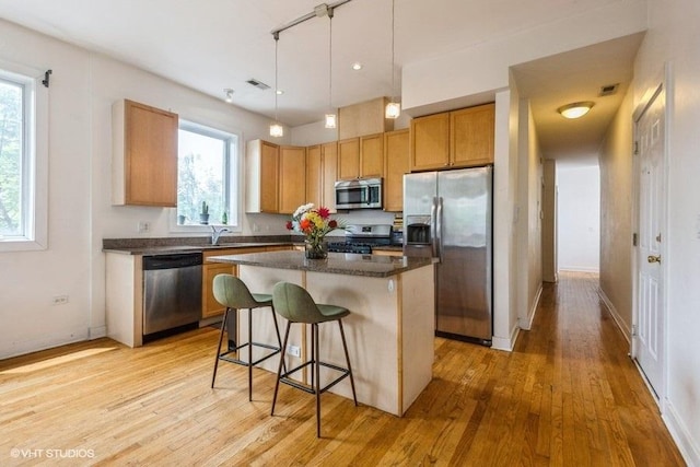 6640 S Maryland Ave Unit 2, Chicago, IL 60637 - kitchen with stainless steel appliances, dark countertops, light wood finished floors, a center island, and a breakfast bar area