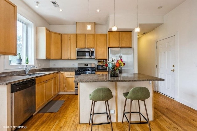 6640 S Maryland Ave Unit 2, Chicago, IL 60637 - kitchen featuring stainless steel appliances, a center island, light wood-style floors, a kitchen bar, and pendant lighting
