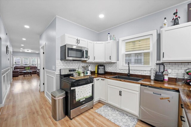 10554 S State St, Chicago, IL 60628 - kitchen with stainless steel appliances, wooden counters, white cabinets, tasteful backsplash, and light wood-type flooring