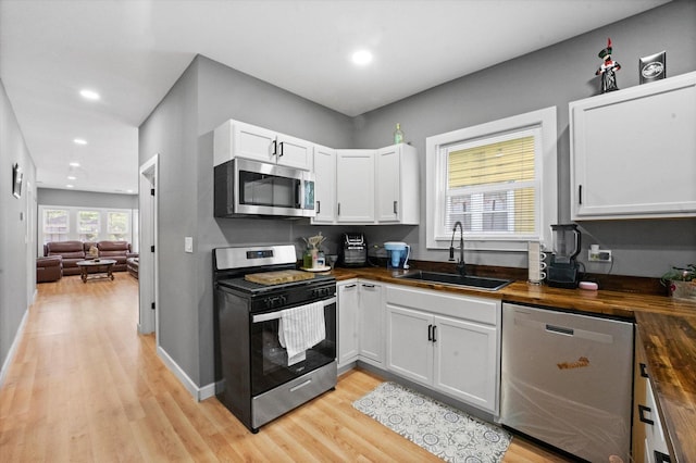 10554 S State St, Chicago, IL 60628 - kitchen with stainless steel appliances, butcher block countertops, light wood-style floors, white cabinets, and recessed lighting