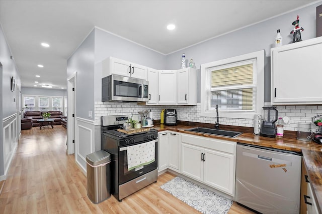 10554 S State St, Chicago, IL 60628 - kitchen with stainless steel appliances, wooden counters, white cabinets, tasteful backsplash, and light wood-type flooring