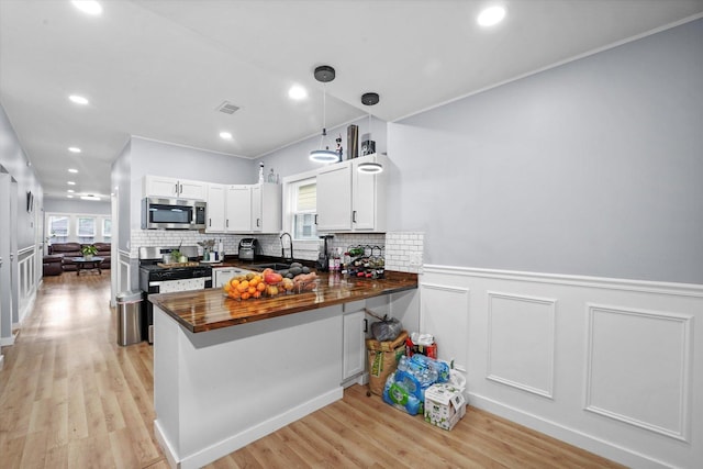10554 S State St, Chicago, IL 60628 - kitchen featuring stainless steel appliances, plenty of natural light, a peninsula, light wood-style floors, and a wainscoted wall
