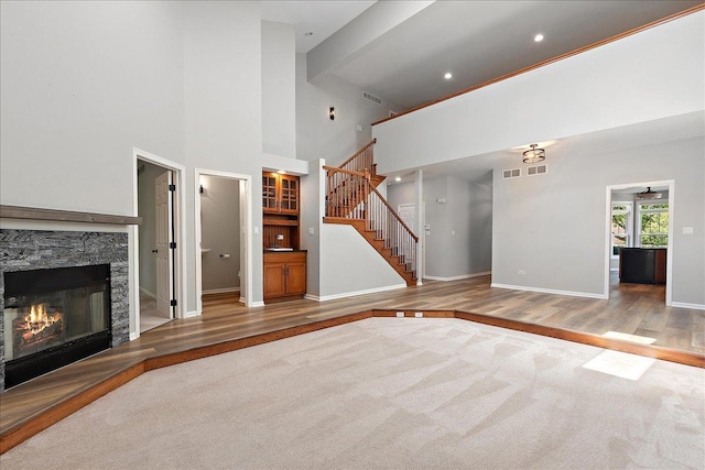 21649 Kent Ct, Frankfort, IL 60423 - unfurnished living room with carpet floors, stairway, a stone fireplace, a towering ceiling, and wood finished floors