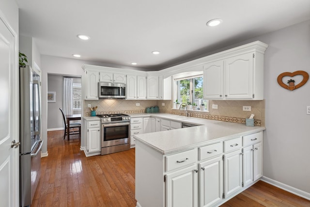 1923 N Carlyle Pl, Arlington Heights, IL 60004 - kitchen featuring appliances with stainless steel finishes, a peninsula, white cabinets, decorative backsplash, and light wood-style flooring