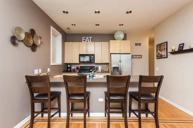 4124 N Kenmore Ave Unit Gs, Chicago, IL 60613 - kitchen with stainless steel refrigerator with ice dispenser, black microwave, a breakfast bar, light wood-type flooring, and stove
