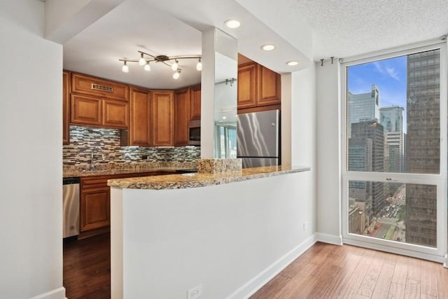 200 N Dearborn St Unit 2402, Chicago, IL 60601 - kitchen with appliances with stainless steel finishes, tasteful backsplash, light stone counters, light wood-style floors, and brown cabinetry