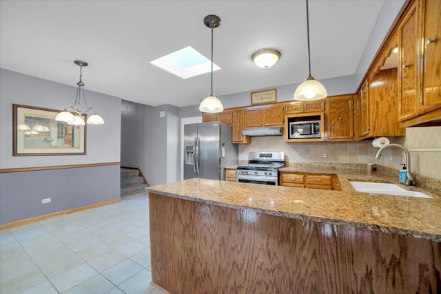 13610 S 84th Ave, Orland Park, IL 60462 - kitchen featuring appliances with stainless steel finishes, under cabinet range hood, a skylight, brown cabinets, and a peninsula