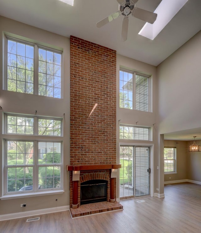 195 Island Ct Unit 195, Schaumburg, IL 60193 - unfurnished living room with a high ceiling, ceiling fan, wood finished floors, a brick fireplace, and a skylight
