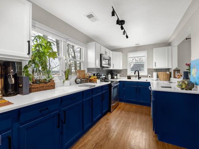 711 Illinois St, Lemont, IL 60439 - kitchen featuring appliances with stainless steel finishes, blue cabinets, white cabinets, and tasteful backsplash