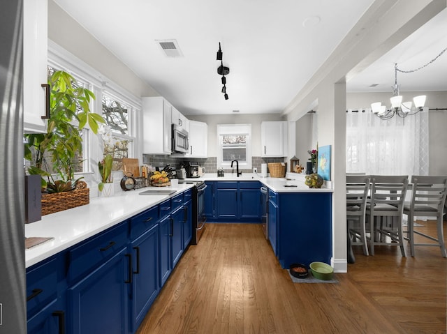 711 Illinois St, Lemont, IL 60439 - kitchen featuring appliances with stainless steel finishes, blue cabinetry, healthy amount of natural light, and a chandelier