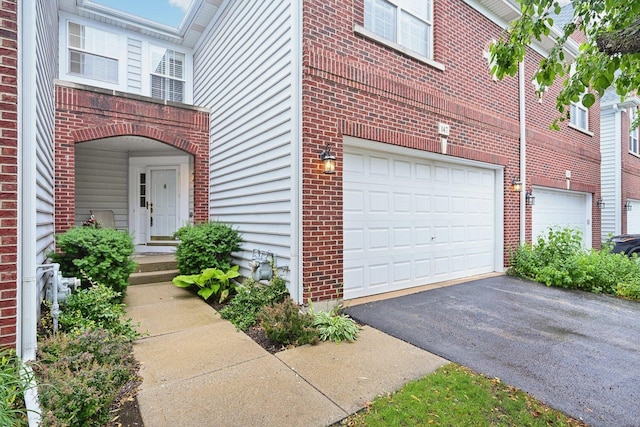 147 Fulbright Ln, Schaumburg, IL 60194 - property entrance featuring a garage, asphalt driveway, and brick siding