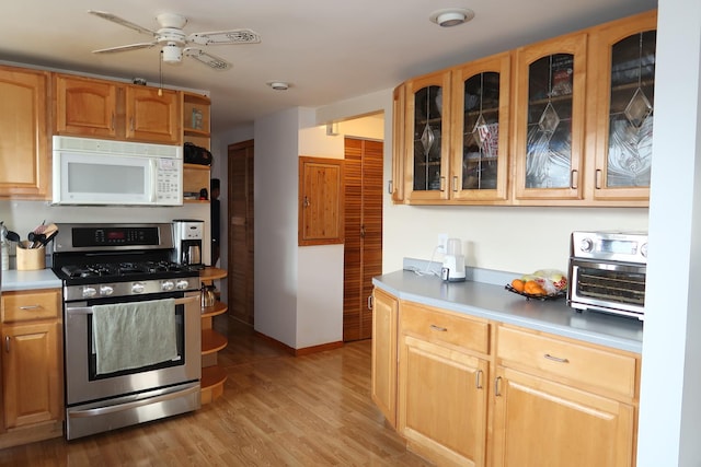 5125 N La Crosse Ave, Chicago, IL 60630 - kitchen featuring stainless steel range with gas stovetop, white microwave, a ceiling fan, light wood-style floors, and light countertops
