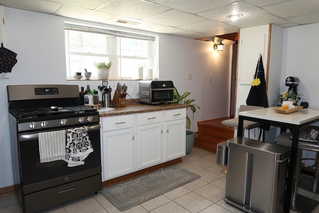 5125 N La Crosse Ave, Chicago, IL 60630 - kitchen featuring stainless steel gas range, white cabinetry, light tile patterned floors, dark countertops, and a drop ceiling