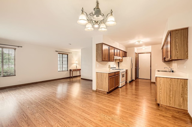 28 W Pheasant Trl Unit 28, Lake In The Hills, IL 60156 - kitchen with white appliances, light wood-type flooring, under cabinet range hood, light countertops, and a chandelier