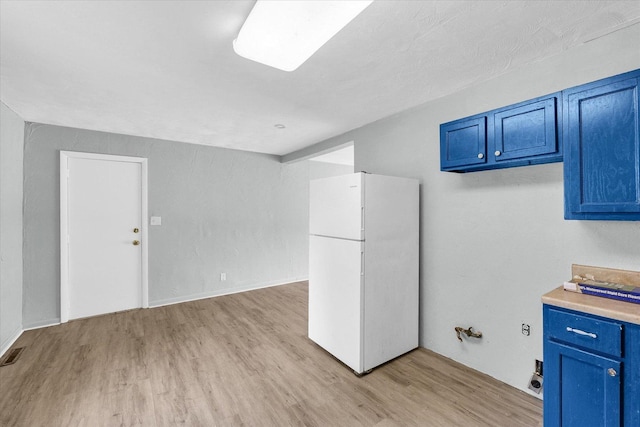1413 Garden Hills Dr, Champaign, IL 61821 - kitchen with freestanding refrigerator, blue cabinets, light wood finished floors, and light countertops