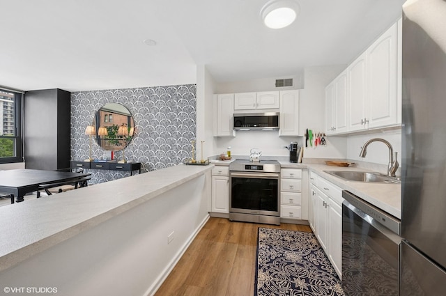 33 E Cedar St Unit 8G, Chicago, IL 60611 - kitchen featuring appliances with stainless steel finishes, light wood-style floors, light countertops, and white cabinetry
