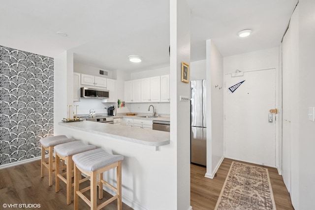 33 E Cedar St Unit 8G, Chicago, IL 60611 - kitchen featuring appliances with stainless steel finishes, a breakfast bar, light wood finished floors, and white cabinetry
