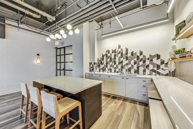 1530 S State St Unit 14O, Chicago, IL 60605 - kitchen with light wood-style flooring, a breakfast bar area, tasteful backsplash, modern cabinets, and hanging light fixtures