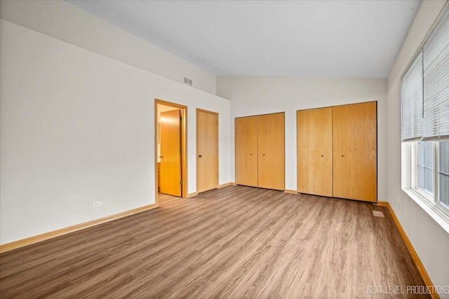1916 Middlebury Dr Unit 1916, Aurora, IL 60503 - unfurnished bedroom featuring vaulted ceiling, multiple closets, and wood finished floors