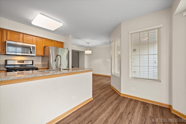 1916 Middlebury Dr Unit 1916, Aurora, IL 60503 - kitchen featuring appliances with stainless steel finishes, brown cabinets, wood finished floors, and pendant lighting