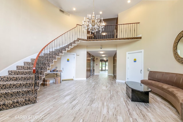 unfurnished living room featuring a high ceiling, stairs, a chandelier, wood finished floors, and recessed lighting