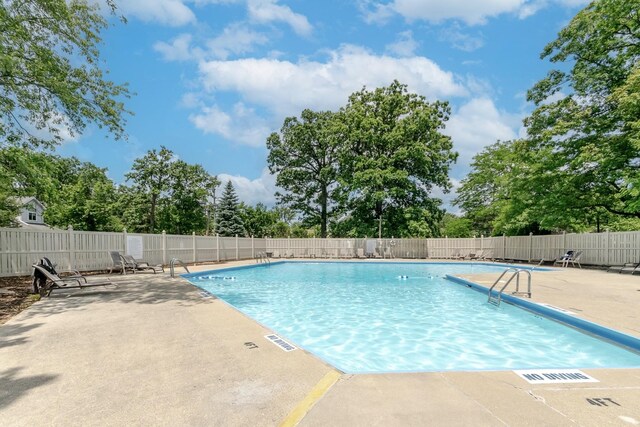 community pool with a patio area and view of scattered trees