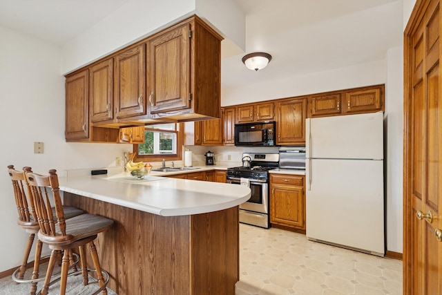 2619 Baldwin Rd, Mchenry, IL 60050 - kitchen with freestanding refrigerator, stainless steel range with gas stovetop, black microwave, a peninsula, and brown cabinetry