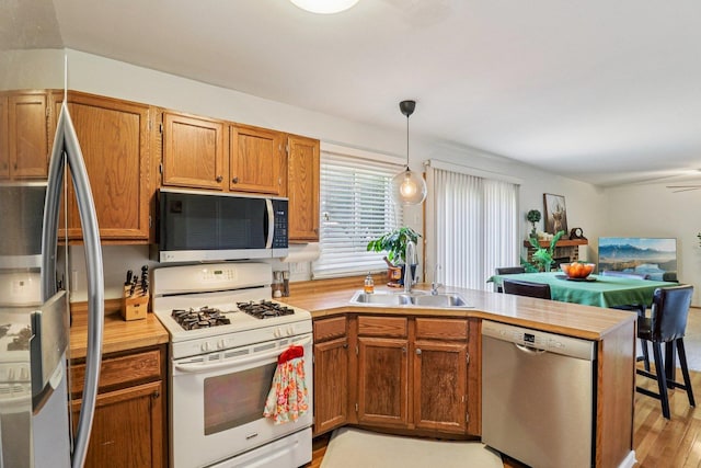 5506 W Chasefield Cir, Mchenry, IL 60050 - kitchen with appliances with stainless steel finishes, a peninsula, pendant lighting, brown cabinetry, and light wood-style flooring