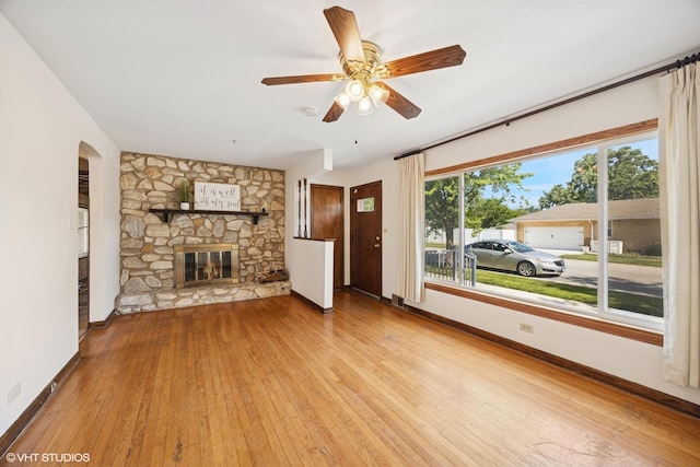 1400 Boeger Ave, Westchester, IL 60154 - unfurnished living room with wood-type flooring, a ceiling fan, arched walkways, and a stone fireplace
