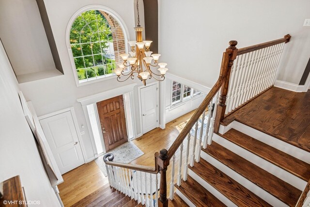 8736 Shade Tree Cir, Lakewood, IL 60014 - foyer featuring light wood-style flooring, a chandelier, a high ceiling, and stairs