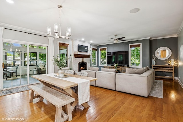 8736 Shade Tree Cir, Lakewood, IL 60014 - dining room with a fireplace, crown molding, light wood-style floors, ceiling fan, and a chandelier