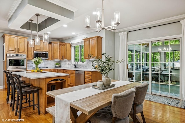 8736 Shade Tree Cir, Lakewood, IL 60014 - kitchen featuring stainless steel appliances, crown molding, light countertops, a kitchen island, and light wood-style floors