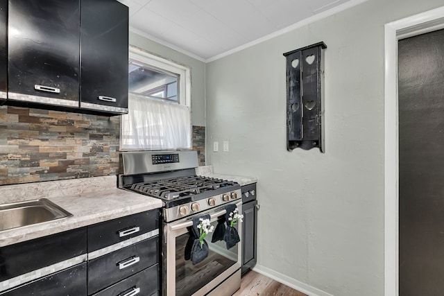 607 E Bridge St, Streator, IL 61364 - kitchen featuring stainless steel gas stove, dark cabinets, crown molding, tasteful backsplash, and light wood-style flooring