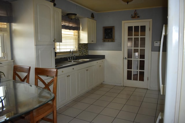 7710 W 81st Pl, Bridgeview, IL 60455 - kitchen featuring dark countertops, a wainscoted wall, white cabinets, ornamental molding, and light tile patterned floors