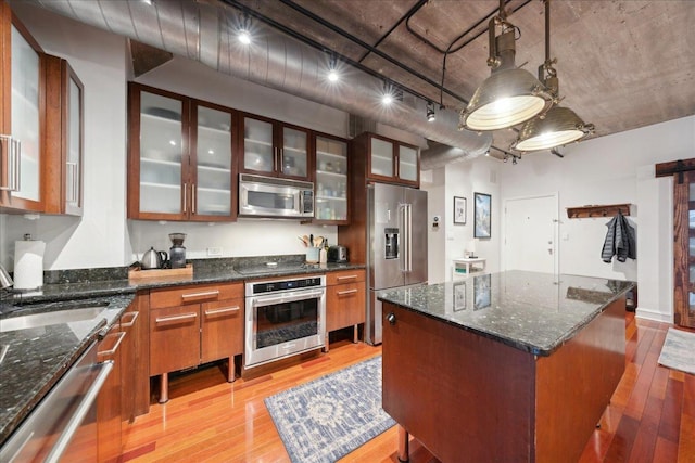 411 W Ontario St Unit 411, Chicago, IL 60654 - kitchen with stainless steel appliances, light wood-style floors, glass insert cabinets, a center island, and hanging light fixtures