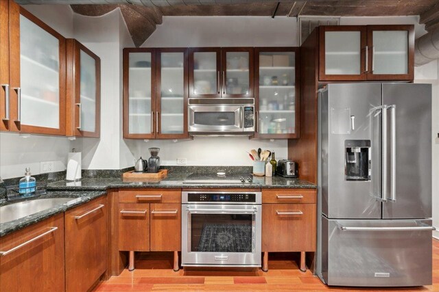 411 W Ontario St Unit 411, Chicago, IL 60654 - kitchen with stainless steel appliances, light wood finished floors, glass insert cabinets, and dark stone countertops