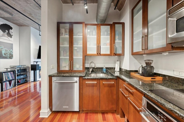 411 W Ontario St Unit 411, Chicago, IL 60654 - kitchen with appliances with stainless steel finishes, light wood-type flooring, brown cabinetry, glass insert cabinets, and dark stone counters