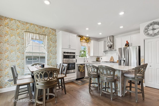 2032 Wentworth Dr, Volo, IL 60020 - kitchen featuring stainless steel appliances, wallpapered walls, wall chimney range hood, white cabinets, and a kitchen island