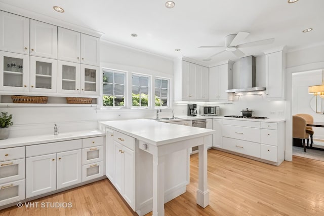 720 Willow Rd, Winnetka, IL 60093 - kitchen with wall chimney range hood, white cabinets, a peninsula, light wood-style floors, and a ceiling fan
