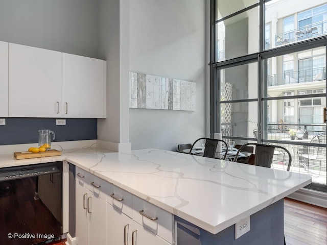 900 N Kingsbury St Unit 967, Chicago, IL 60610 - kitchen with dishwasher, a high ceiling, white cabinets, light wood-style flooring, and light stone counters
