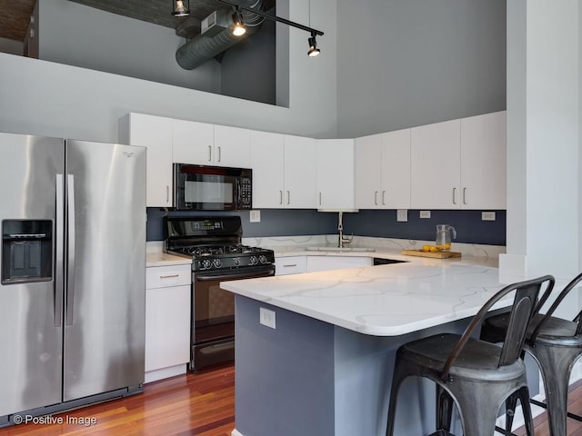 900 N Kingsbury St Unit 967, Chicago, IL 60610 - kitchen featuring black appliances, a high ceiling, a peninsula, dark wood-style floors, and light stone countertops