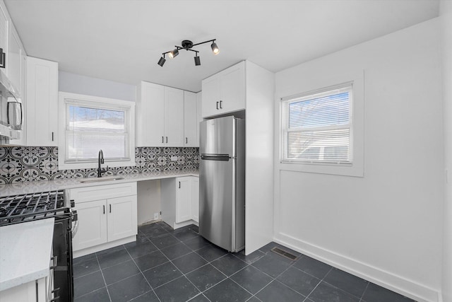 329 Blackhawk Dr, Park Forest, IL 60466 - kitchen featuring freestanding refrigerator, gas stove, dark tile patterned flooring, tasteful backsplash, and white cabinets
